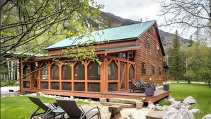 A wooden cabin with a deck, outdoor seating, and a view of mountains. - Great for Families! Woodsy Sanctuary in Mc Leod (McLeod)