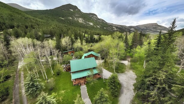 A lodge with a green roof, surrounded by dense forest and mountains. - Great for Families! Woodsy Sanctuary in Mc Leod (McLeod)