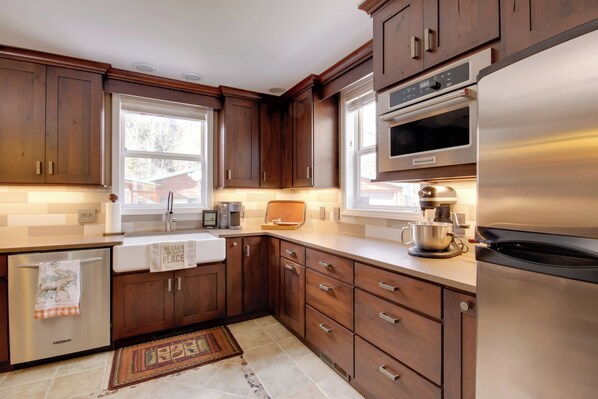 A modern kitchen with wooden cabinets, stainless steel appliances, and a window providing natural light.