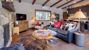 A cozy living room with a fireplace, leather sofa, and a stone wall. - Great for Families! Woodsy Sanctuary in Mc Leod (McLeod)