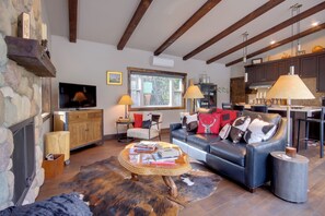A cozy living room with a fireplace, leather sofa, and a stone wall. - Great for Families! Woodsy Sanctuary in Mc Leod (McLeod)