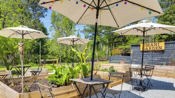 An outdoor seating area with wooden tables and chairs, surrounded by raised garden beds with plants. - Group Entertainment Oasis! 3-unit Lithonia Getaway (Lithonia)