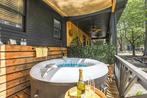 Ein Whirlpool mit Holzterrasse, eine Champagnerflasche und zwei Gläser auf einem Tisch.