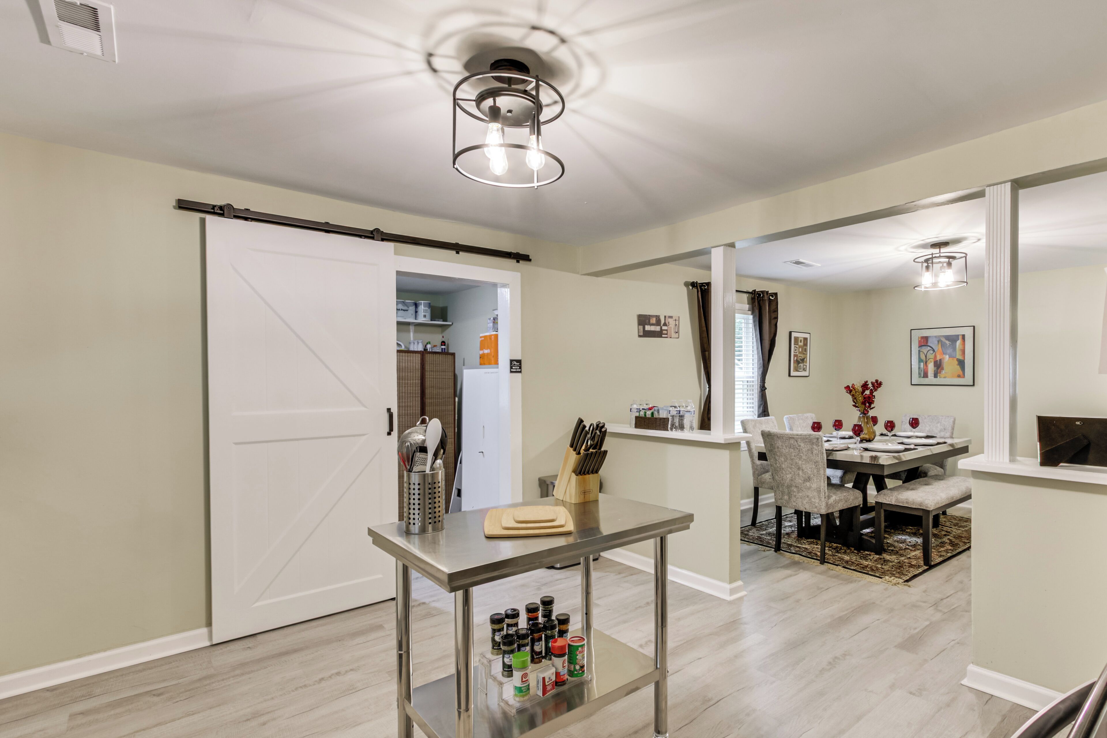 A modern kitchen with a dining area, a sliding door, and a ceiling light fixture.