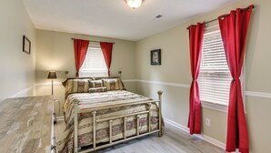A bedroom with a bed, two windows with red curtains, a ceiling light, and a framed picture on the wall. - 4 Mi to Dtwn! 'carolyn's Cottage' in Decatur (Decatur)