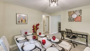 A dining area with a table set for four, a vase with flowers, and a modern chandelier. - 4 Mi to Dtwn! 'carolyn's Cottage' in Decatur (Decatur)