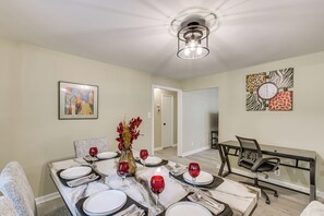 A dining area with a table set for four, a vase with flowers, and a modern chandelier. - 4 Mi to Dtwn! 'carolyn's Cottage' in Decatur (Decatur)