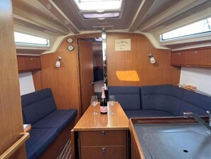 Ein kompakter Innenraum mit einer Sitzecke, einem kleinen Tisch mit Flasche und Gläsern sowie einem Fenster.