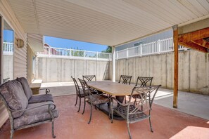 Un patio couvert avec une table et des chaises, un banc et une clôture blanche.