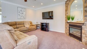 A living room with a sectional sofa, a fireplace, a ceiling fan, and a flat-screen TV. - Near Hill Afb! Dual-unit Home w/ Deck & Patio (Clearfield)