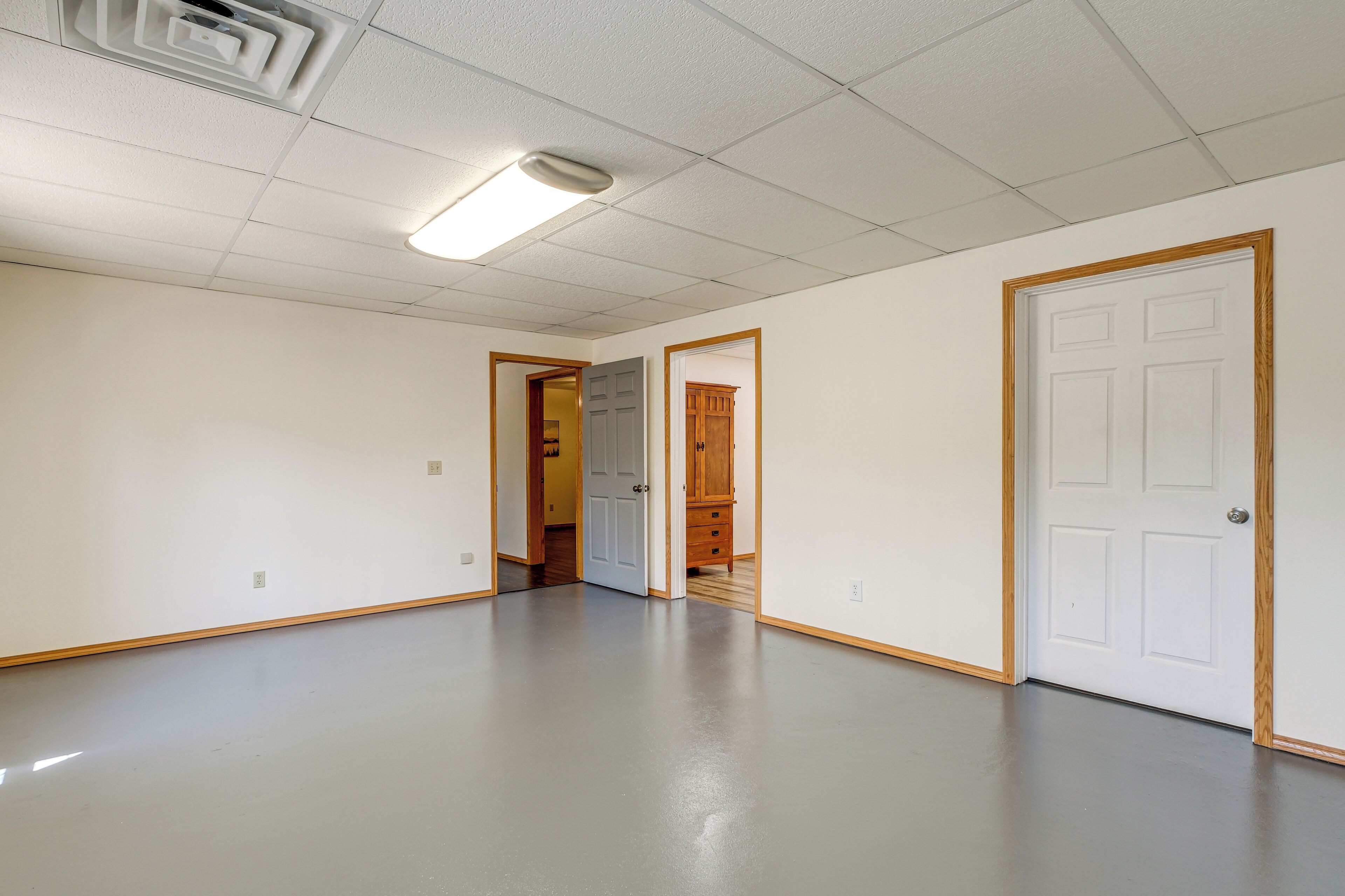 A hallway with a polished floor, white walls, and wooden-framed doors.