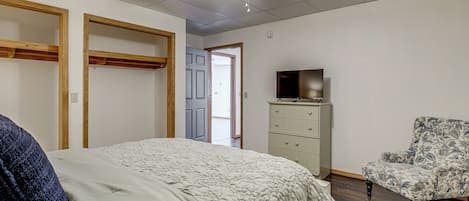 Un dormitorio con cama, cómoda, silla, ventilador de techo y una puerta que da a otra habitación.