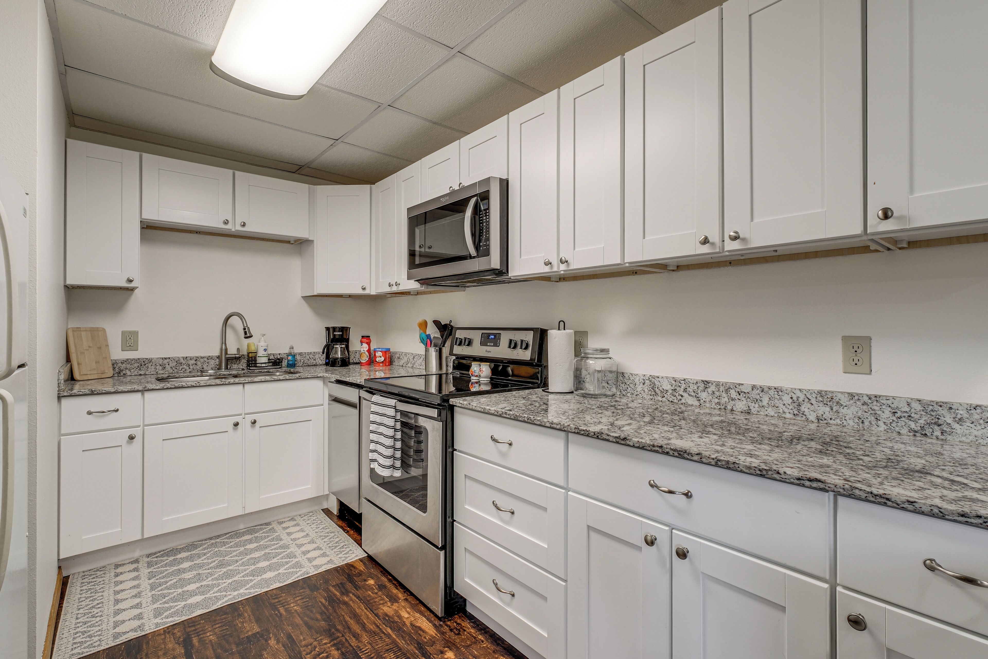 A kitchen with white cabinets, a stainless steel oven, a microwave, and a granite countertop.