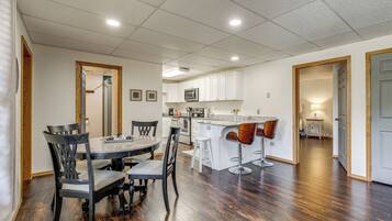 Una cocina moderna con armarios blancos, una isla central y un comedor con sillas de madera oscura.