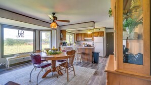 A modern kitchen with wooden cabinets, a dining area with a round table and chairs, and a large window with a view of the outdoors. - Peaceful Fulton Farm Retreat w/ Outdoor Space! (Fulton)