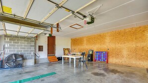 A garage with a concrete floor, a brick wall, a table with chairs, a fan, and a dartboard. - Peaceful Fulton Farm Retreat w/ Outdoor Space! (Fulton)