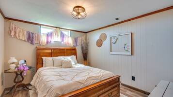 Un dormitorio con cama de madera, una mesita de noche con lámpara y una ventana con cortinas.