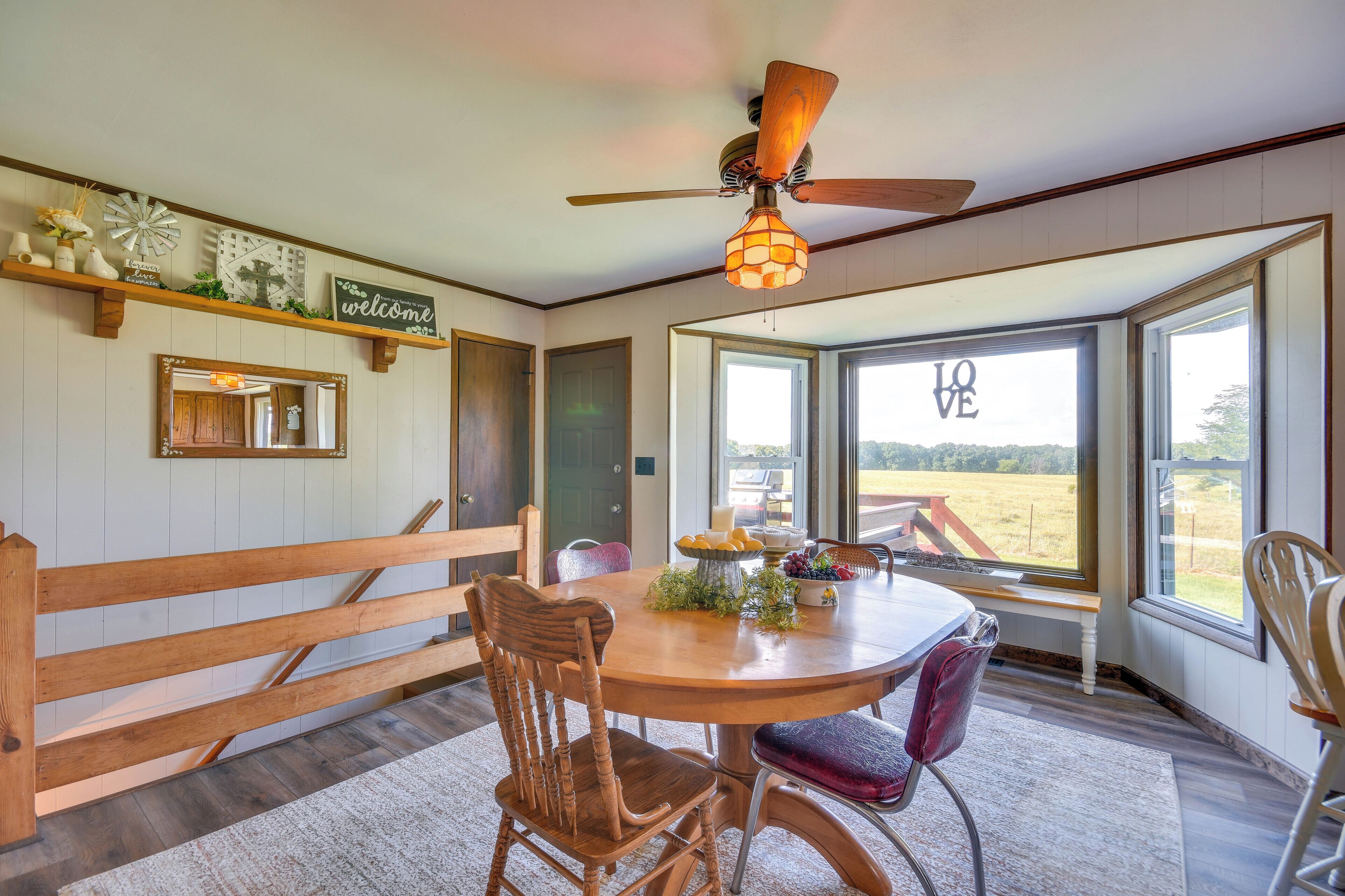A dining area with a round table, wooden chairs, and a ceiling fan.