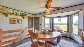 A dining area with a round table, wooden chairs, and a ceiling fan.