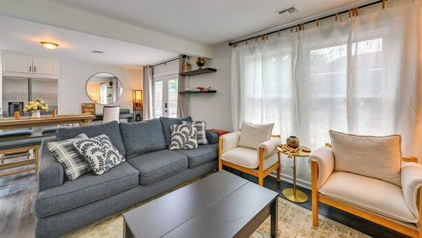 A modern living room with a grey sofa, two armchairs, a coffee table, and a kitchen area in the background. - Walk to Train! Updated Apt in Huntington Station (Huntington Station)