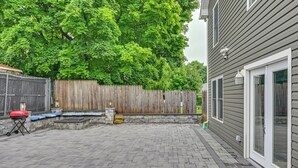Ein Patio mit Backsteinfassade, Holzzaun und einem Haus mit einer Schiebeglastür.