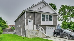 Ein zweistöckiges Haus mit Veranda, Garage und Auffahrt.