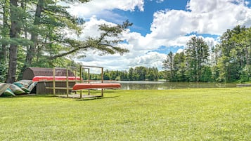 A grassy area with a wooden structure, a red object, and a body of water.