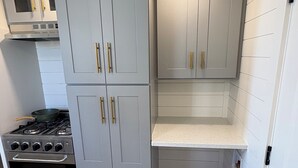 A compact kitchen with grey cabinets, a built-in stove, and a countertop. - Oceanfront Tiny Retreat On Wheels, Fall Package + 2 Bikes (Holden Beach)