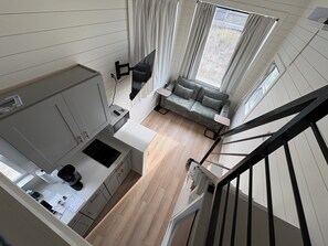 Ein kompakter Wohnbereich mit Küchenzeile, einer Couch und einer Treppe.