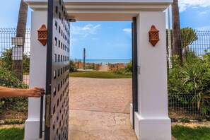 A gated entrance with a clear view of the sea, a pathway leading to the gate, and a white building structure. - Costalita 2BR, Pool, Garage & Direct Beach Access (Estepona)