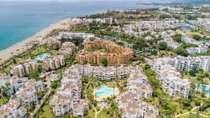 A coastal residential area with a central cluster of apartment buildings, a beach, and a swimming pool. - Costalita 2BR, Pool, Garage & Direct Beach Access (Estepona)