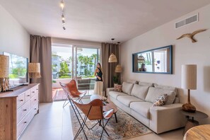 Ein modernes Wohnzimmer mit einer Couch, einem Couchtisch, einem Fernseher und einem Essbereich mit Stühlen.