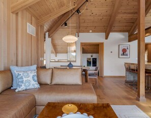 A cozy living room with a wooden ceiling, a sofa with cushions, a coffee table, and a dining area with chairs. - Unit 35C Lot 8 Oceanhaus (The Sea Ranch)