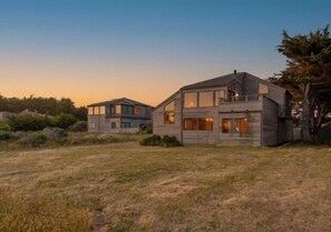 A modern two-story house with a large front yard and a tree to the right. - Unit 35C Lot 8 Oceanhaus (The Sea Ranch)
