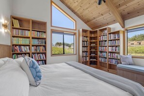 Une chambre avec un grand lit, de nombreuses étagères et une vue sur l’extérieur.