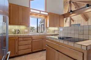A modern kitchen with wooden cabinets, a large window, and a tiled backsplash. - Unit 35C Lot 8 Oceanhaus (The Sea Ranch)
