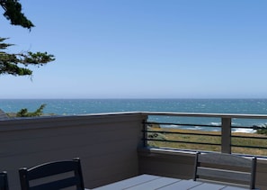 A balcony with a view of the ocean, a table, and two chairs. - Unit 35C Lot 8 Oceanhaus (The Sea Ranch)