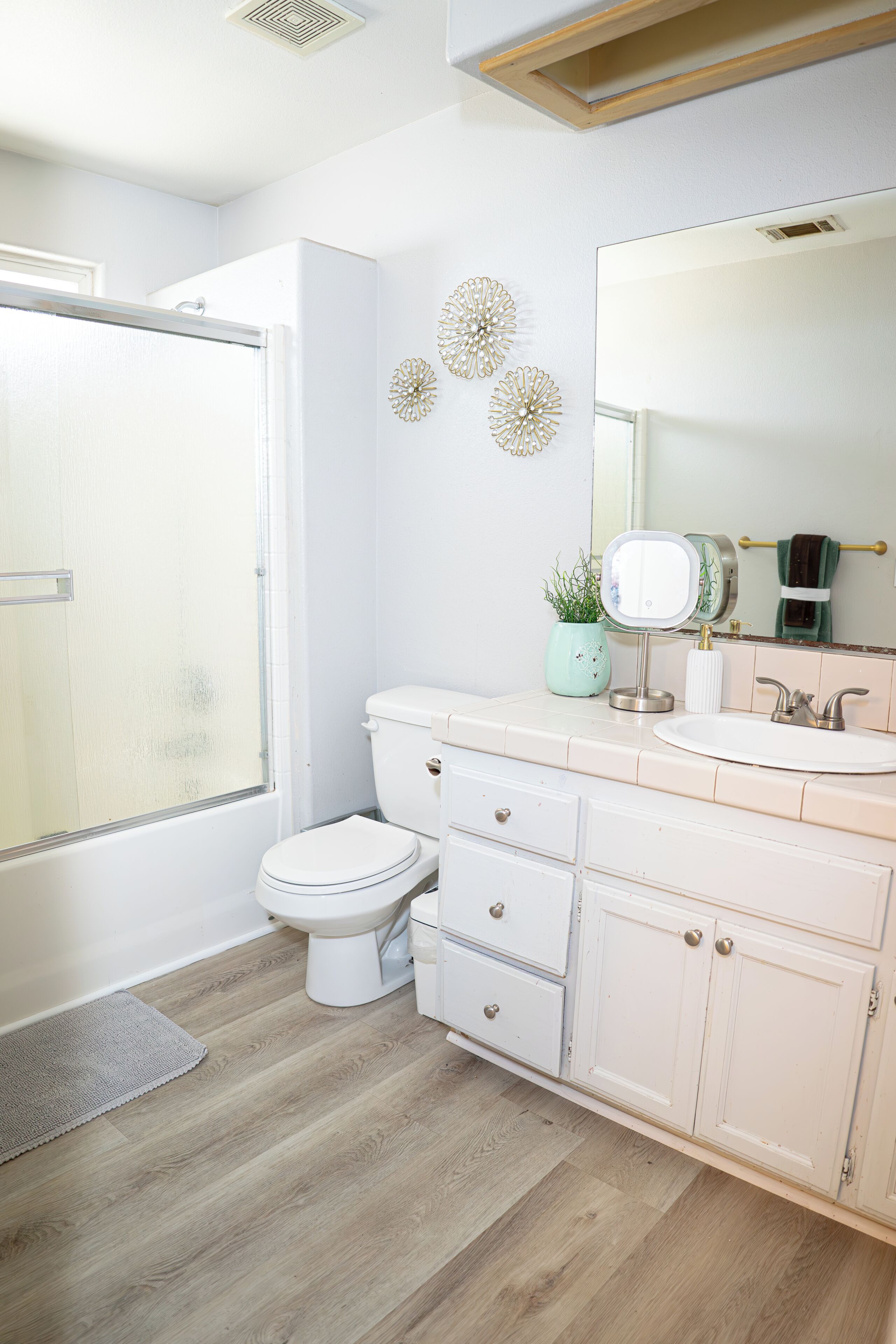A bathroom with a toilet, sink, vanity, and a shower.