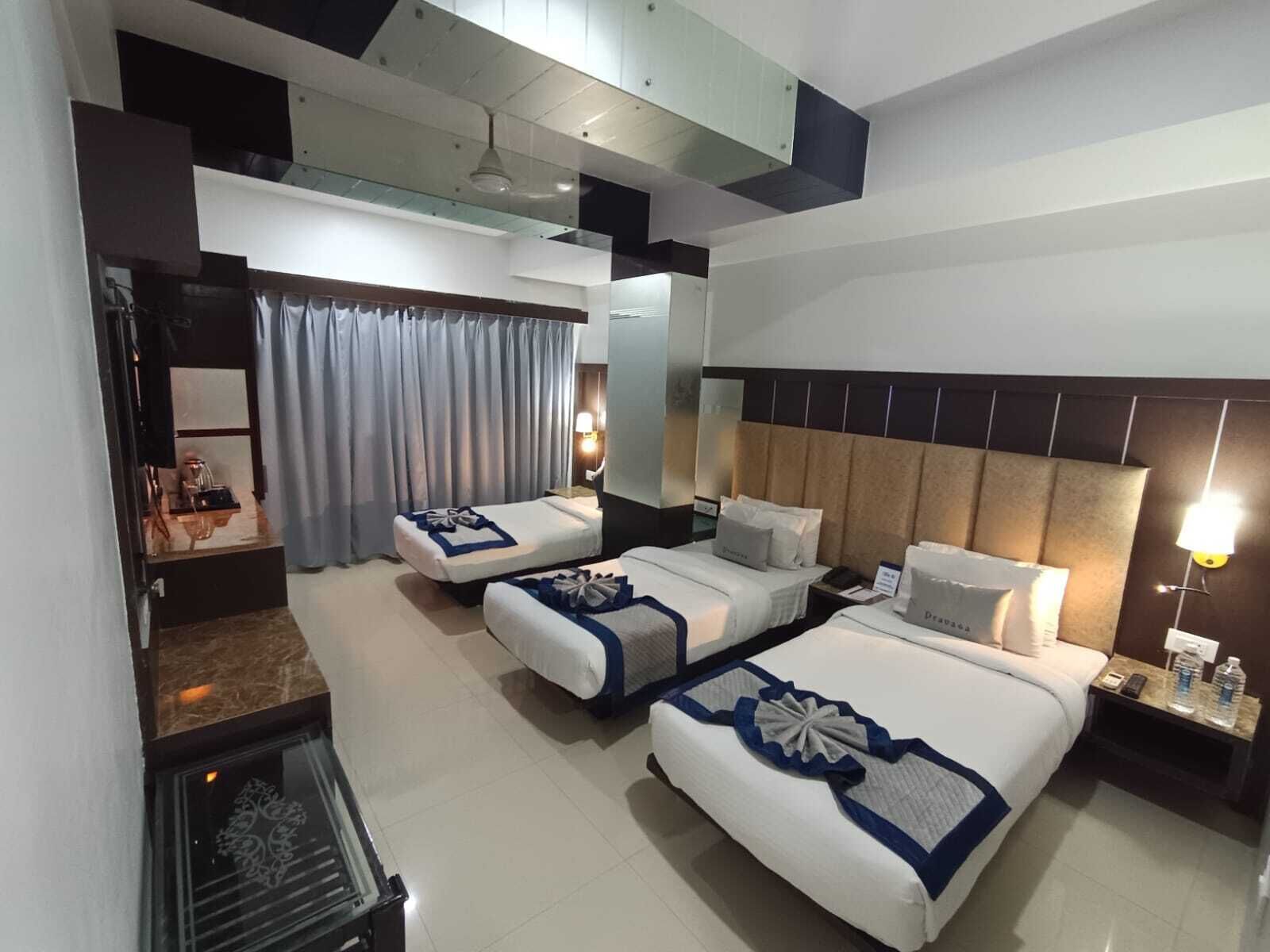 A hotel room with two beds, a large mirror, a ceiling fan, and a small table with a lamp.