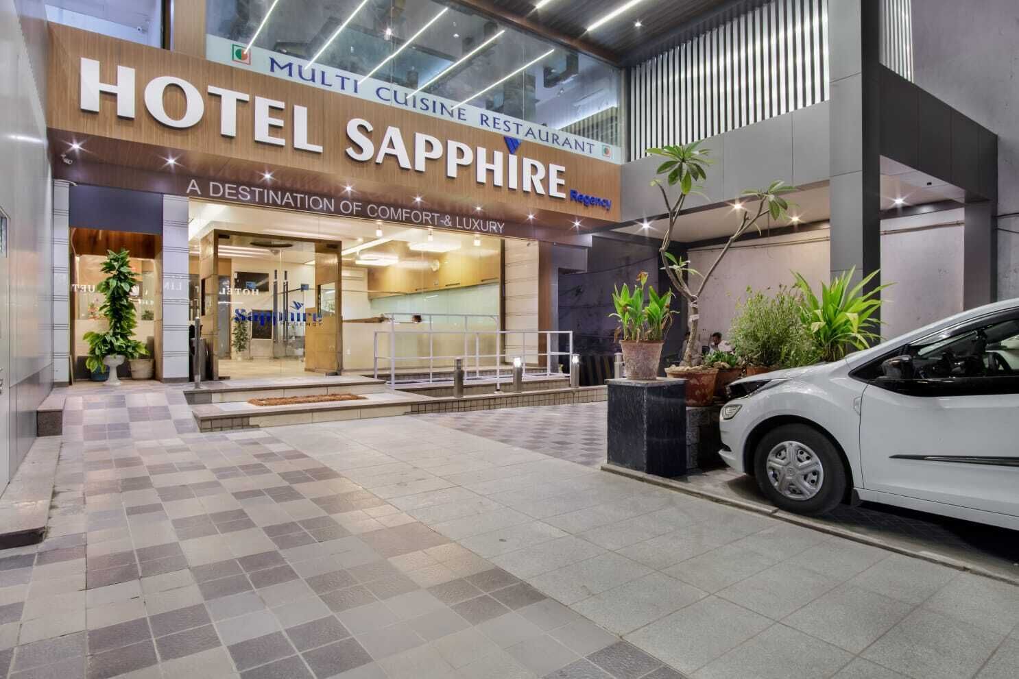 L’entrée d’un hôtel, avec une enseigne indiquant « HÔTEL SAPPHIRE », et un restaurant proposant une cuisine variée.