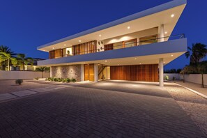 A modern two-story house with a stone facade, a balcony, and a driveway. - NEW luxury vacation villa with a pool next to Jan Thiel Beach (Jan Thiel)