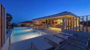Ein moderner Poolbereich mit Liegestühlen und Essbereich, mit Blick auf ein Wohngebäude.