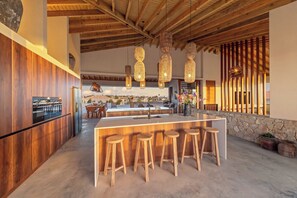 A modern kitchen with a central island, wooden stools, and hanging pendant lights. - NEW luxury vacation villa with a pool next to Jan Thiel Beach (Jan Thiel)