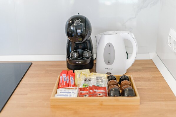 Una cucina con una macchina del caffè, un bollitore e un vassoio con cialde e capsule di caffè.