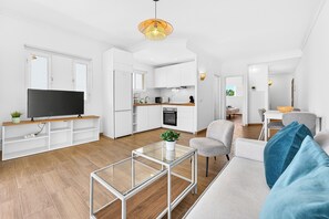 Ein modernes Wohnzimmer mit einem Flachbildfernseher, einem Glastisch und einem grauen Sofa.