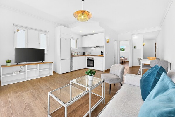 A modern living room with a flat-screen TV, a glass coffee table, and a grey sofa. - Home Holidays 152 (San Miguel de Abona)
