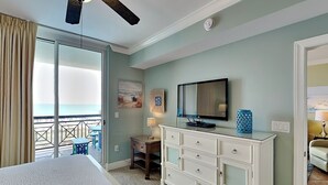 Una camera da letto con un letto, una cassettiera, una televisione e una scrivania con una lampada.
