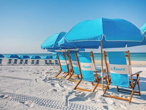 A beach with rows of blue beach chairs and umbrellas, some labeled "Azure." - Azure #306 | Gulf Front Condo with Stunning Views and Resort Amenities (Fort Walton Beach)