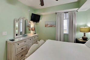 Un dormitorio con cama, cómoda, televisor y un cuadro en la pared.