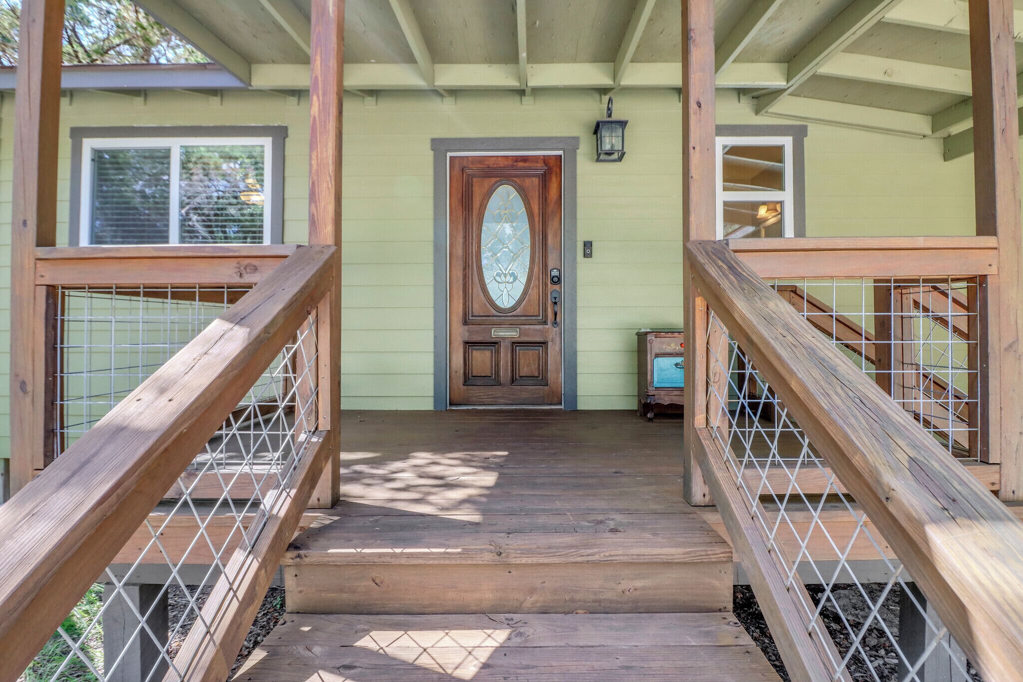 A wooden staircase leading to a door with a glass panel, a small table, and a lantern on the porch.